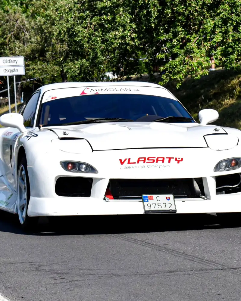 Biela pretekárska Mazda RX-7 s logom ARMOLAN.sk na čelnom skle počas pretekov na Slovensku